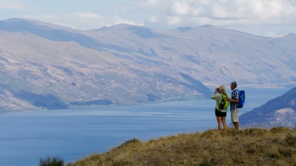 活跃的高加索夫妇享受徒步旅行使用双筒望远镜户外的 Remarkables 湖瓦卡蒂普新西兰 — 图库视频影像