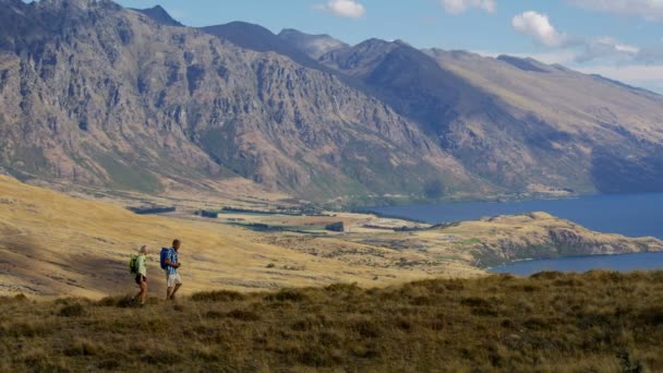 健康退休的白种夫妇与背包享受退休徒步旅行的 Remarkables 湖瓦卡蒂普新西兰 — 图库视频影像