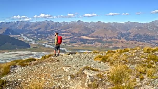 リュックはニュージーランドの南の島の風景の中のハイキングを楽しむで若いアクティブな白人男性ハイカーの空中ドローン — ストック動画