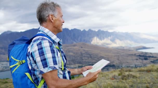 高加索高级男性徒步旅行和计划游览新西兰 Remarkables 湖瓦卡蒂普的阅读地图 — 图库视频影像