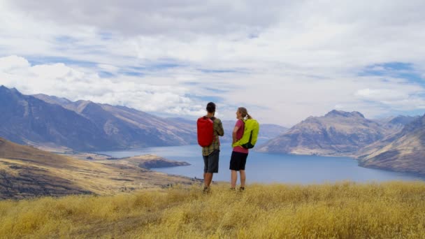 そのハイキングの冒険に若い白人男性と女性ハイカーが リマーカブルズ オタゴ ニュージーランドの旅します — ストック動画