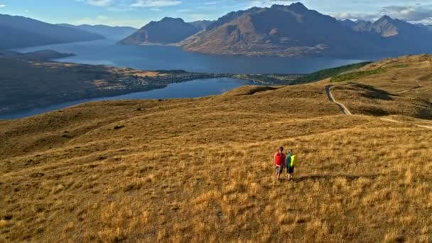 リマーカブルズ オタゴ新しいニュージーランドのハイキングの冒険探検の白人男性と女性ハイカーの空中ドローン — ストック動画