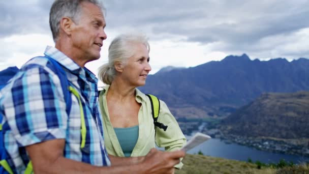 幸せな先輩白人カップル リマーカブルズ ニュージーランド フィヨルドランドの地図を読んで楽しんでハイキングを楽しむ — ストック動画