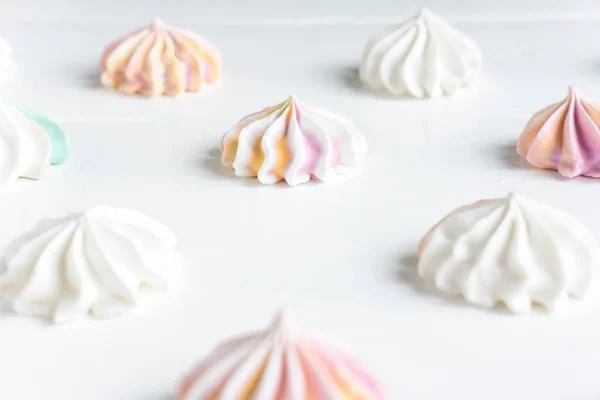 Color meringues. Background for a banner with sweets. Multicolored meringues on a white wooden background. banner, cafe, sweet shop.