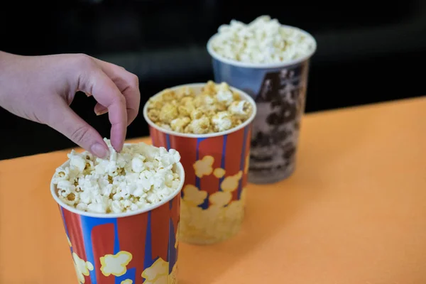 Photos of popcorn in cups. Popcorn near the cinema. Watching a movie, a cartoon with popcorn.