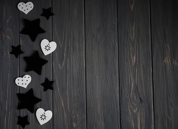 Stars of black color and white hearts on a white wooden background. Background for teens with stars