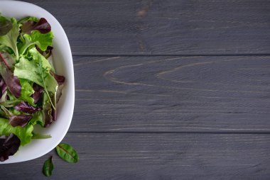 Koyu ahşap zemin üzerine yeşil salata ile plaka. Yemek, Restoran, kafe bir afiş için arka plan.