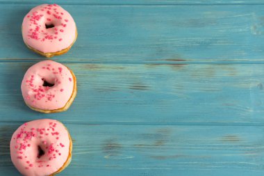 Çörek ve mavi ahşap arka plan üzerinde marshmallow ile fotoğraf. Tatlılar karanlık bir arka plan üzerinde. Pembe çörek