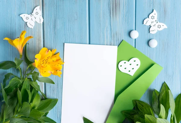 Mock up blank paper, mail envelope on a dark wooden background with natural flowers of white color and butterflies. Blank, frame for text. Greeting card design with flowers. Aalstroemeria on wooden ba — Stock Photo, Image