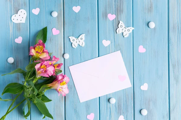 Mock up blank paper, mail envelope on a dark wooden background with natural flowers of white color and butterflies. Blank, frame for text. Greeting card design with flowers. Aalstroemeria on wooden ba