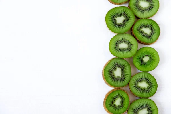 Bakgrund med kiwi skivad från sida. Ram för banner med färska tropiska frukter. Naturliga Kiwi på vit bakgrund. Platt lekmanna, top view. — Stockfoto