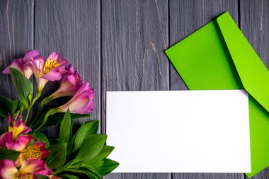 Pembe renk doğal çiçekler ile koyu ahşap arka plan üzerinde boş kağıt kadar mock. Boş, metin çerçevesi. Çiçek ile tebrik kartı. Ahşap arka planda aalstroemeria. Düz yatıyordu, üst görünüm.