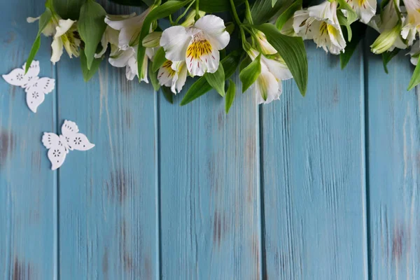 Rahmen für Grußworte mit natürlichen Blumen, Schmetterlingen. Hintergrund für ein Banner blauer Farbe mit Blüten der Alstroemeria. flache Lage, Draufsicht. — Stockfoto