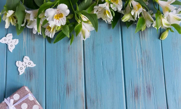 Rahmen für Grußworte mit natürlichen Blumen, Schmetterlingen, Geschenk. Hintergrund für ein Banner blauer Farbe mit Blüten der Alstroemeria. flache Lage, Draufsicht. — Stockfoto