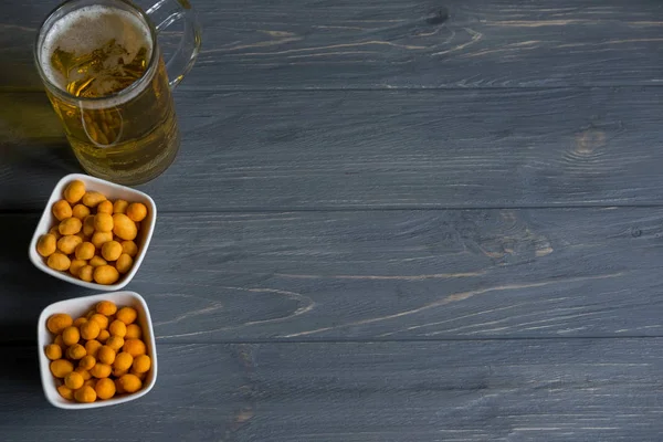 Foto de um copo de cerveja com nozes. Cerveja leve em um fundo escuro. Fundo com nozes para cerveja — Fotografia de Stock