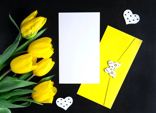 Mock up blank with flowers on a black background. Yellow tulips with copysceis. Frame for text with flowers. View from above