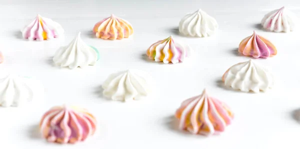 Multi-colored meringue on a white background. Sweets on the photo. Pattern with meringue on a white background. Sweet holidays — Stock Photo, Image