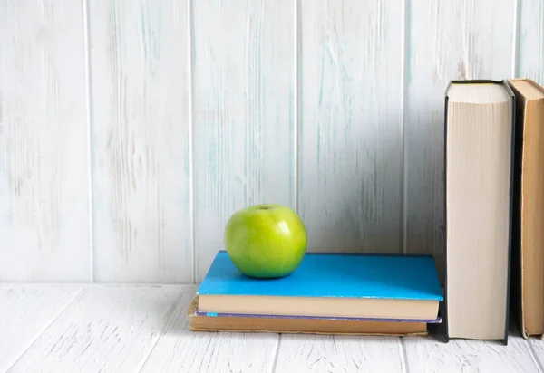 Photo of a stack of books with an apple and a place for an inscription on a wooden background. Accounting, school, study, students. Concept on the topic of study