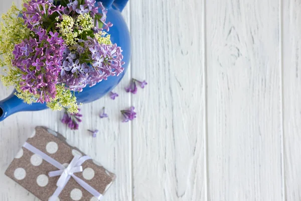 Flores lila sobre un fondo de madera con un lugar para una inscripción. Banner floral con flores lila y regalo. Fondos florales para la tarjeta de felicitación —  Fotos de Stock