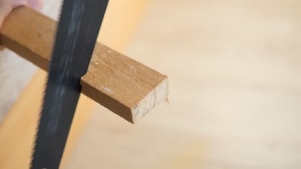 男子用锯子把木板锯掉了 用手锯锯一块木头 住宅建设和建筑 — 图库视频影像