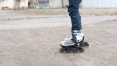 Çocuk silindirler üzerinde toprak bir yolda gidemez. Paten kaymayı öğrenen bir çocuk.