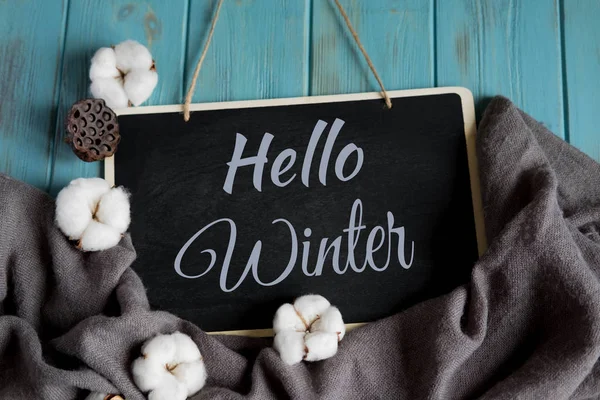 Bonjour carte postale d'hiver. Bannière d'hiver avec châle gris chaud, fleurs de coton sur un fond en bois bleu — Photo