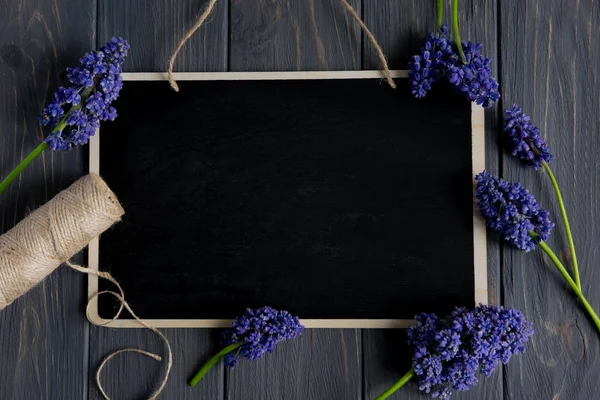 Schöne lila Blumen auf grauem Holzgrund mit Platz für eine gratulierende Inschrift. Rahmen für Grußbanner, Postkarte. flache Lage, Draufsicht. — Stockfoto