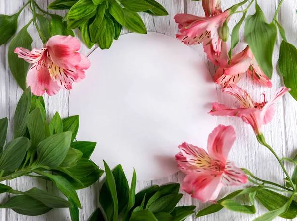 Mock up blank paper, mail envelope on a dark wooden background with natural flowers of white color and butterflies. Blank, frame for text. Greeting card design with flowers. Aalstroemeria