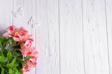 Pembe çiçekler ve kelebekler ile açık ahşap arka plan metin afiş için arka plan. Boş, metin için çerçeve. Çiçeklerle tebrik kartı tasarımı. Ahşap arka planda Alstroemeria. Yukarıdan görüntüle