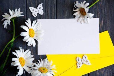 Tebrik yazıt, promosyonlar, papatyalar ve ahşap bir arka plan üzerinde bir zarf ile indirimler için mektup mockup. Posta için yazı ve afiş için temel. Düz döşeme, üst görünüm.