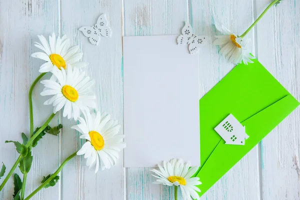 Letter mockup for greeting inscription, promotions, discounts with daisies and an envelope on a wooden background. The basis for the lettering and banner for the mailing. Flat lay, top view.