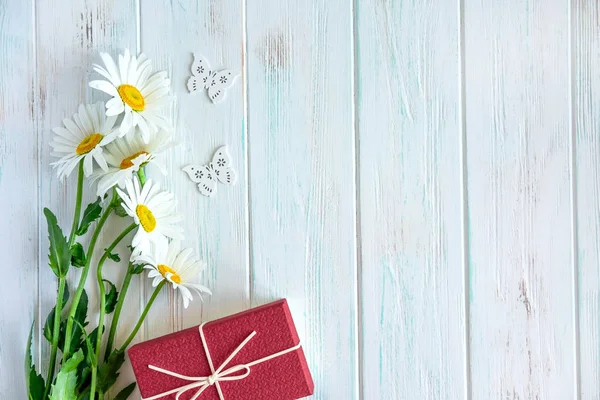 Hintergrund für Grußkarte mit Gänseblümchen auf Holzgrund und Geschenk. Rahmen für Text mit Gänseblümchen auf hölzernem Hintergrund. Blumen-Hintergrund-Banner. flache Lage, Draufsicht. — Stockfoto