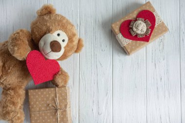 Bir ışık ahşap arka planda hediyeler ile bir kalp ve kutuları ile oyuncak ayı. Doğum günü tebrik kartının tasarımı. Sevgililerin tebrik yazıt metin için çerçeve, anneler günü