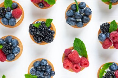 Tartlets, yumuşak peynir ve ahududu, böğürtlen, yaban mersini çilek ile Desen. Lezzetli ve sağlıklı tatlılar. Çilek ve nane ile tatlılar Fotoğraf. Tatlı ve Berry Desen
