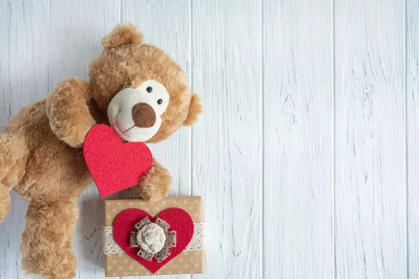 Toy bear with a heart and boxes with gifts on a light wooden background. The design of the birthday greeting card. Frame for the text of the congratulatory inscription of lovers, Mother's Day