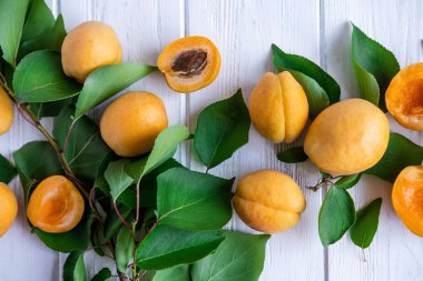 Yeşil yaprakları ile Olgun kayısı meyve ışık ahşap arka plan üzerinde yakın çekim. Pektin içeren yaz meyvesi.