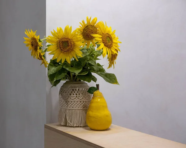 A bouquet of sunflowers on a table with a handmade ceramic pear and a place for copy space. Autumn greeting background. Autumn banner design for advertising, discounts, promotions