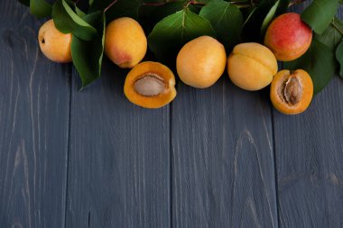 Kayısı ile arka plan. Yeşil yaprakları ve gri ahşap arka plan üzerinde kopyalama alanı için yer ile taze kayısı Fotoğraf. Kayısı yakın çekim. Tarım, reklam, diyet ve sağlıklı beslenme