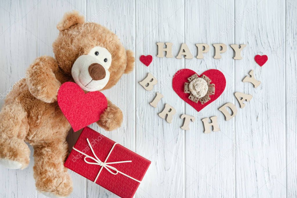 Toy bear with a heart and boxes with gifts on a light wooden background. The design of the birthday greeting card. Frame for the text of the congratulatory inscription of lovers, Mother's Day