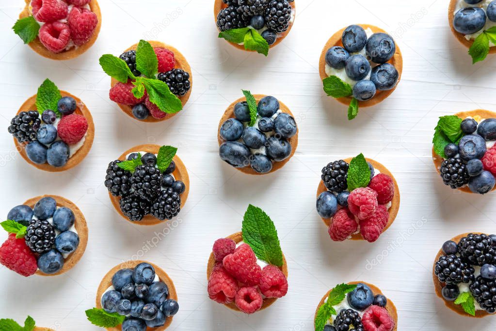 Useful tartlets with blueberries, blueberries, raspberries in the shape of a heart isolated on white background. Heart made of sweets and sweets