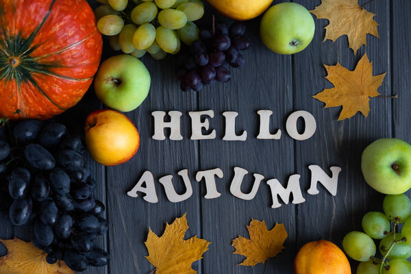 Буквы Hello Autumn из деревянных букв. Осенний баннер с тыквой, виноградом, яблоками, нектарином на сером деревянном фоне. Осенний сбор урожая на ферме, сад
