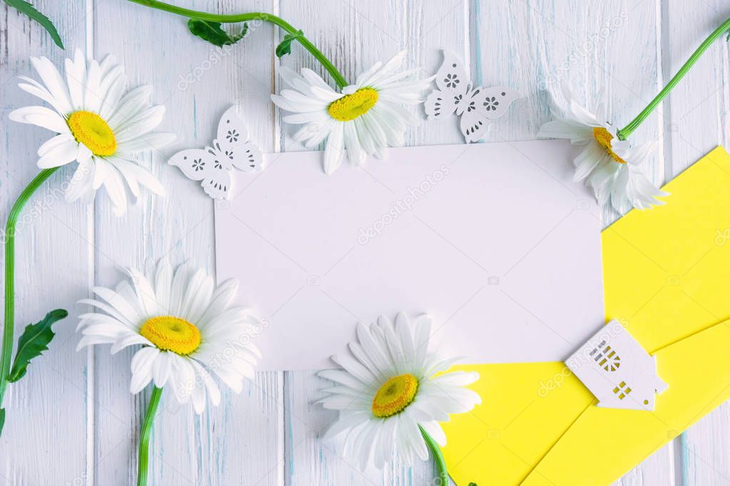 Mock up for letter, mailing with camomiles on a gray wooden background. Natural wildflowers with a place for an inscription, a promotional code, a greeting