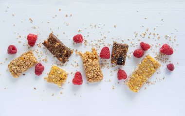 Hafif ahşap arka plan üzerinde tahıl ve taze ahududu çilek ile Barlar. Sağlıklı kahvaltı, doğru beslenme, vejetaryenler ve kilo kaybı için vitamin menüsü. Granola Barlar, Lif ve Çilek