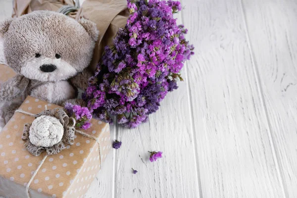 Ramo de flores silvestres secas con caja de regalo y oso sobre un fondo de madera. Diseño de tarjeta de felicitación con flores . — Foto de Stock