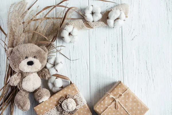 Χειμερινή σύνθεση με ξηρά φυτά, κουτιά δώρου και ένα αρκουδάκι σε ξύλινο φόντο. Πρότυπο για μια ευχετήρια κάρτα με θέση για κείμενο, γράμματα. Προσομοίωση πρόσκλησης μέσω email — Φωτογραφία Αρχείου