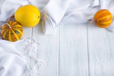 Kumaş ve küçük balkabaklarıyla aydınlık ahşap zemin. Balkabaklarıyla sonbahar arkaplanı. Yukarıdan görüntüle