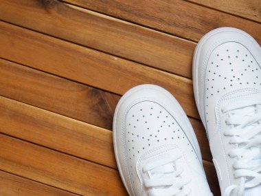 Tahta arka planda beyaz erkek spor ayakkabıları.