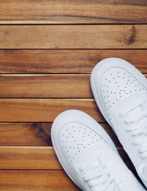 Tahta arka planda beyaz erkek spor ayakkabıları.