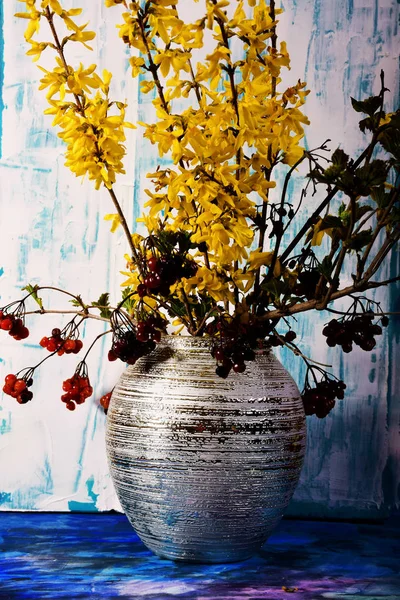 Flowering freesia and last year\'s viburnum in a vase