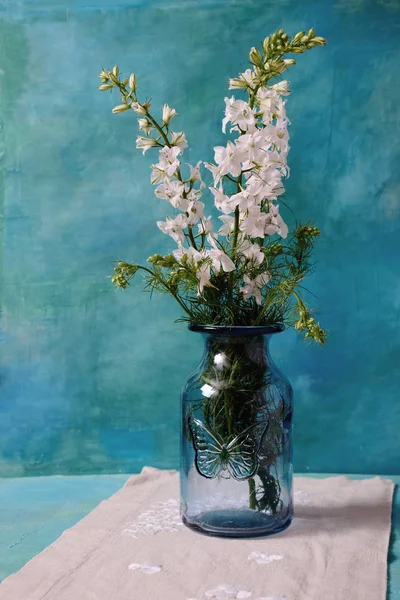 Vase with wildflowers in a glass blue vase on a linen napkin